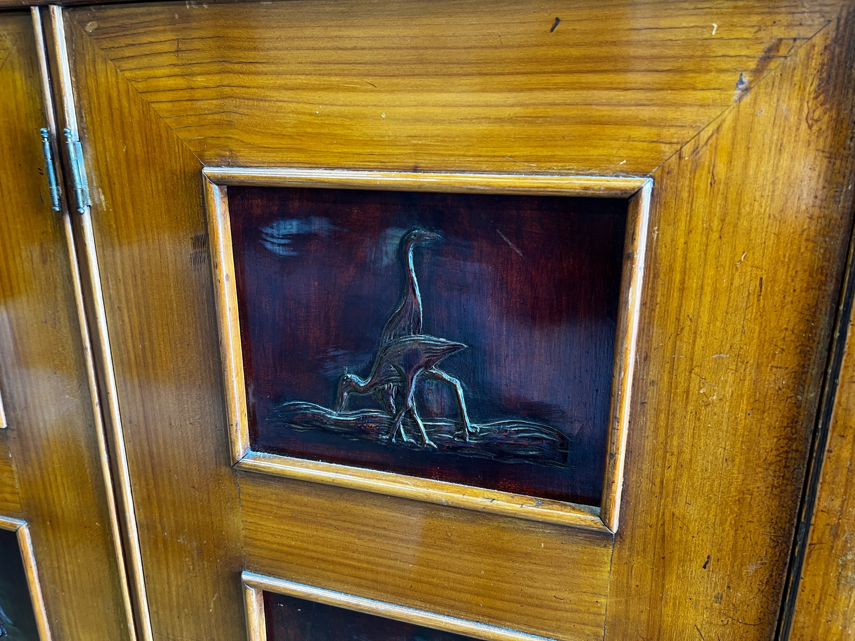 A mid century continental side cabinet, the panelled doors carved with antelope and exotic birds, width 212cm, depth 50cm, height 146cm